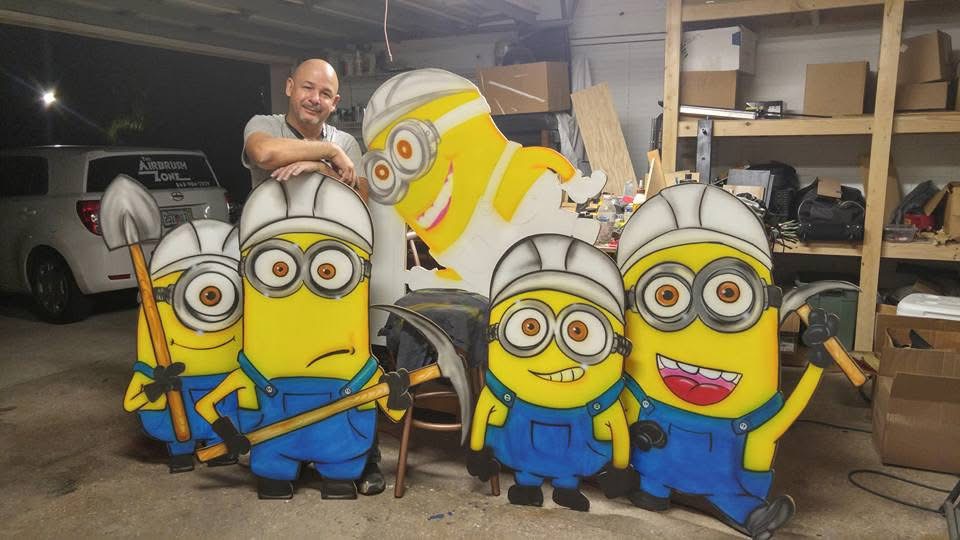 Efrain Matos in his Haines City workshop with hand-cut, airbrushed Minion character cutouts